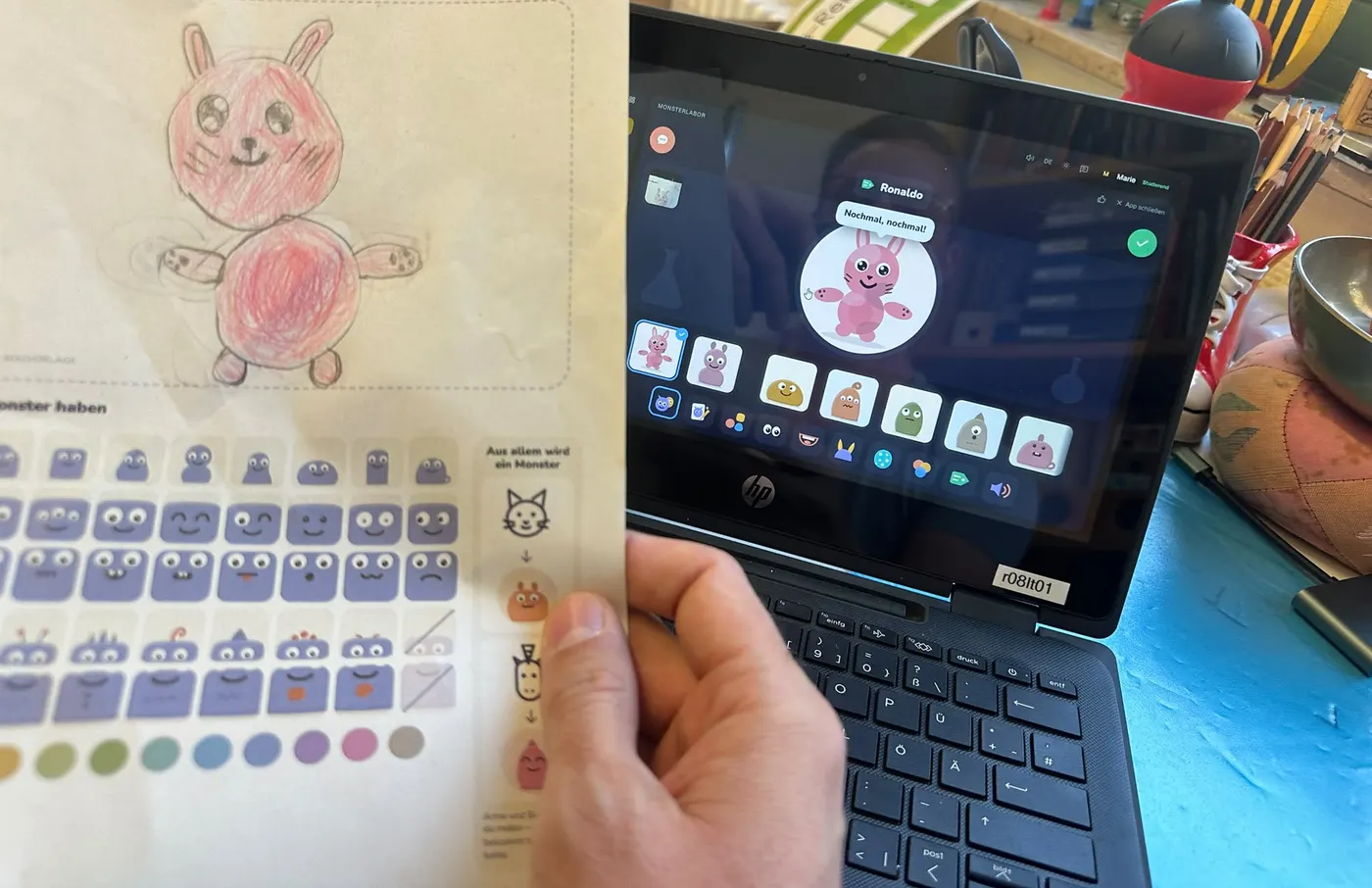 Gemalter Hase auf der Malvorlage neben einem Laptop, auf dem das Monsterlabor denselben Hasen als Monster zeigt